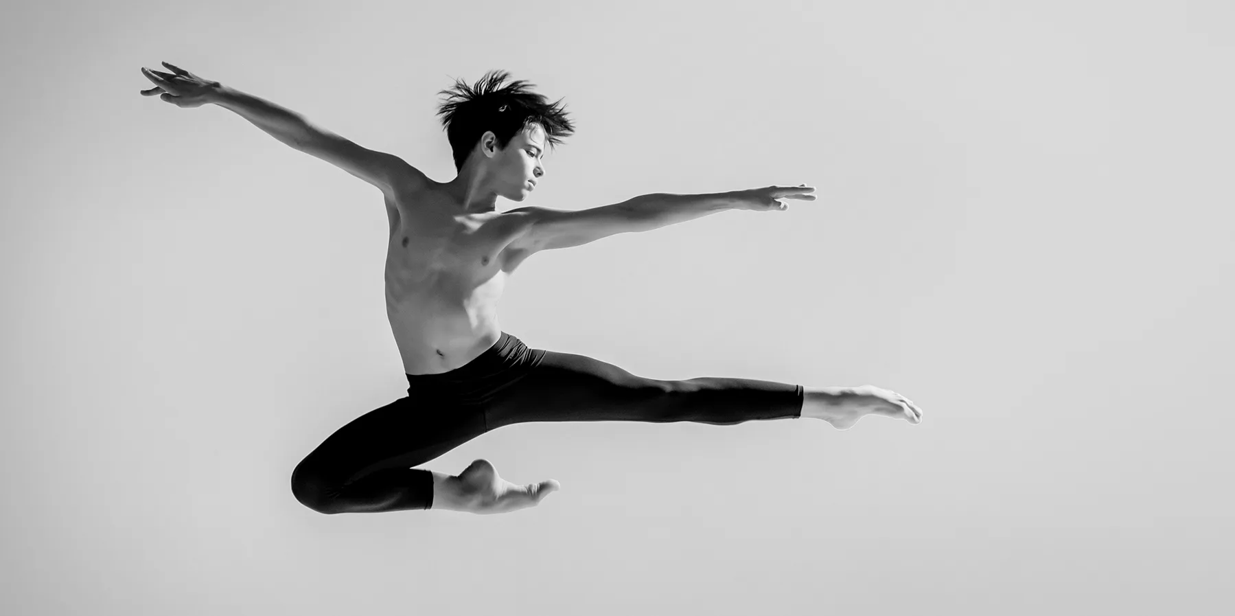 slender-teen-ballet-boy-jumps-barefoot-under-colored-light